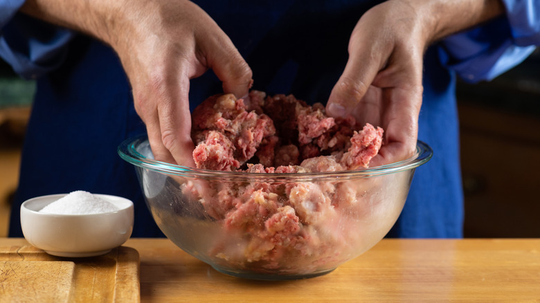 Person mixing raw ground meat with hands