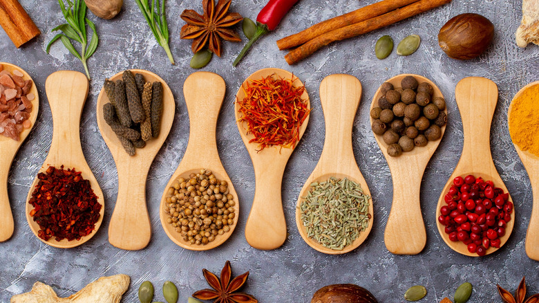 Varied herbs and spices on wooden spoons