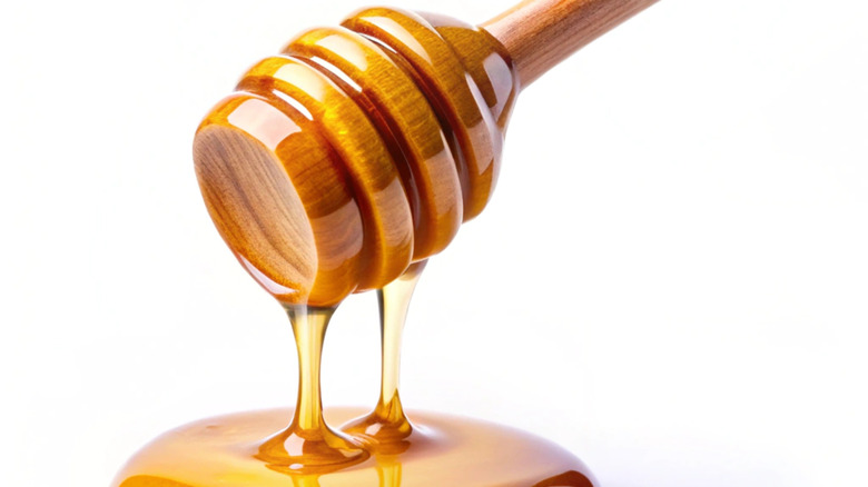 Honey drizzling from wooden dipper