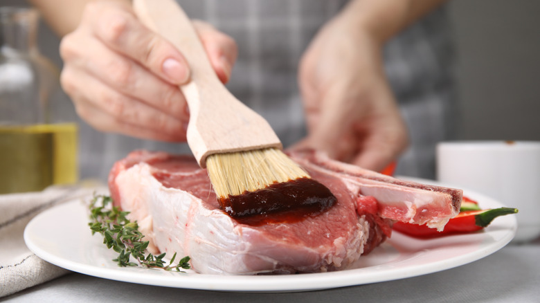 Spreading marinade on a raw steak