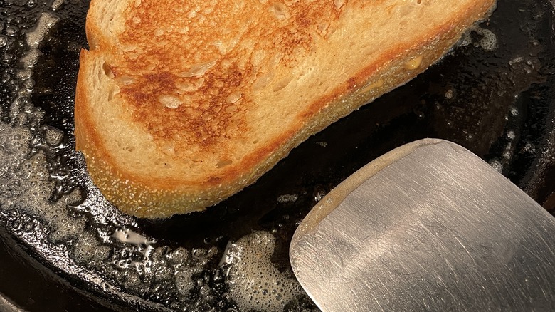 Metal spatula flipping grilled cheese