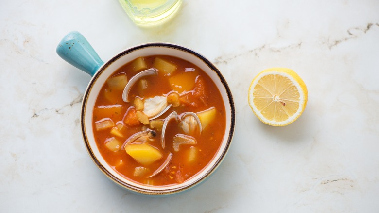 Bowl of Manhattan clam chowder next to lemon