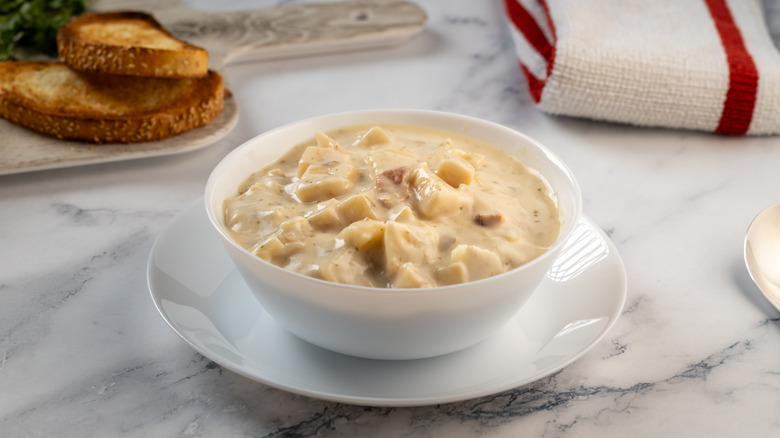 Potato chowder in white bowl on white plate