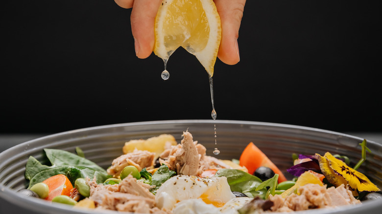 Person squeezing lemon juice into tuna salad