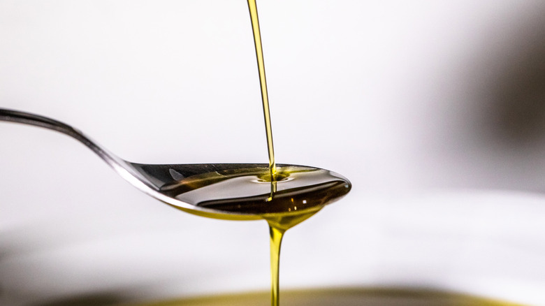 Olive oil poured onto silver spoon