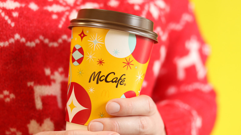 Hands hold McDonald's Christmastime cup of coffee