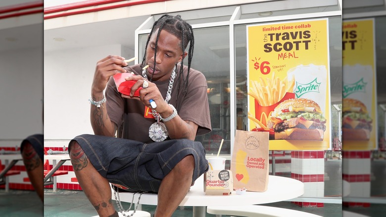 Travis Scott sits on table eating McDonald's meal