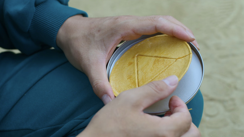 A triangle Dalgona candy in the hands of a player