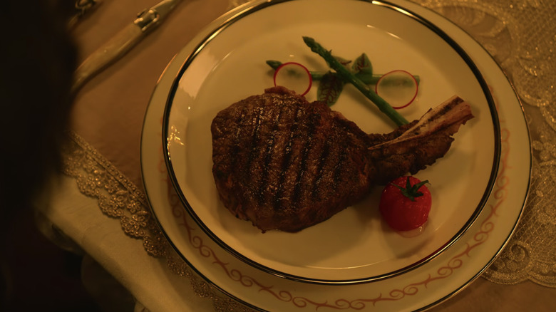 A large juicy cut of steak on the bone with radishes and asparagus as garnish