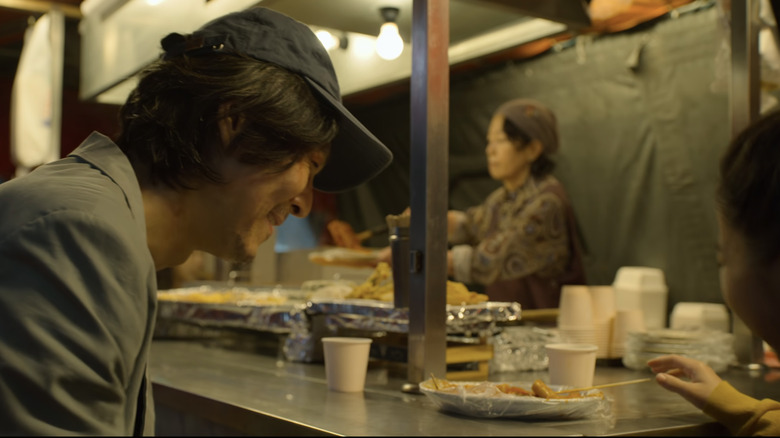 Gi-hun and his daughter smile as they share tteokbokki at a street stand