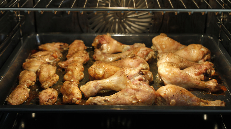 Chicken legs and wings baking on sheet pan in oven