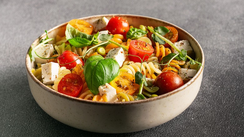 Bowl of pasta salad with spinach, tomatoes, and feta