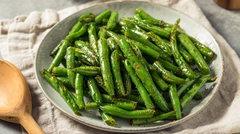 Plate of cooked green beans covered in oil and seasonings