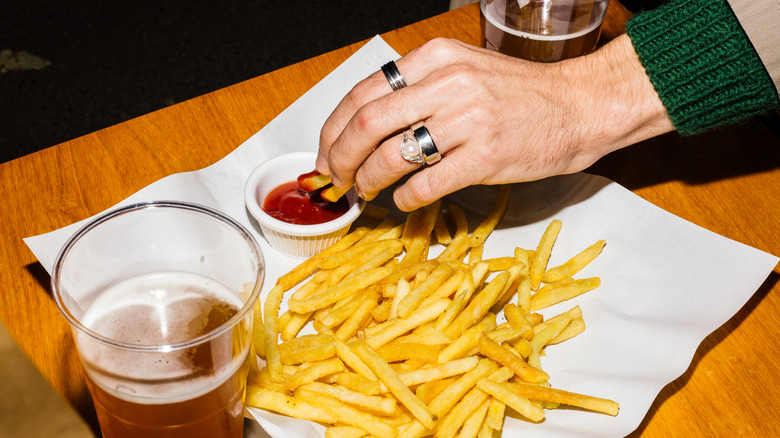 Hand dipping fries into ketchup