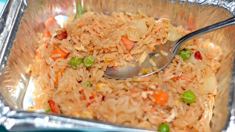 Fried rice in aluminum takeout container with spoon