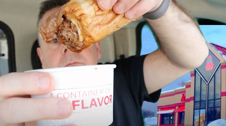 A person holding an Arby's Classic French Dip and Swiss Sandwich