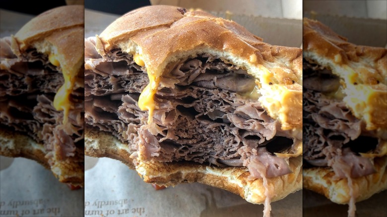 A bitten Arby's Half Pound Beef and Cheddar Sandwich