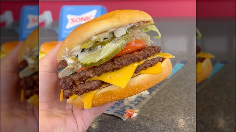 Person holding a Super Sonic Bacon Double Cheeseburger