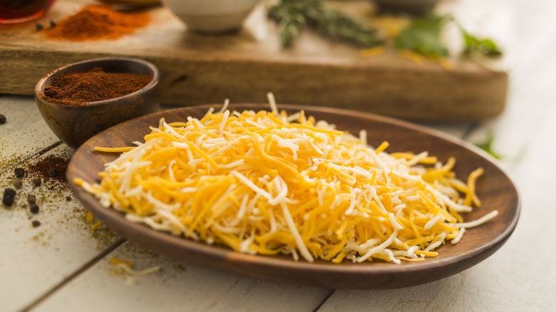 Bowl of shredded cheddar cheese with spices