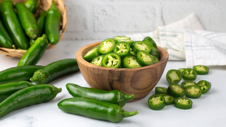 Sliced and whole jalapenos on countertop