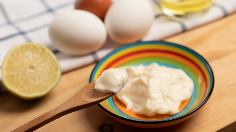 Spoonful of mayo next to bowl, lemon, and eggs