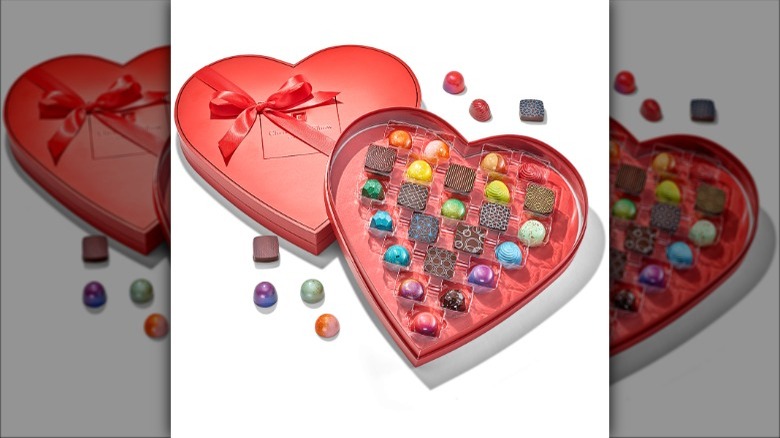 Colorful chocolates are displayed in a pink heart-shaped box.