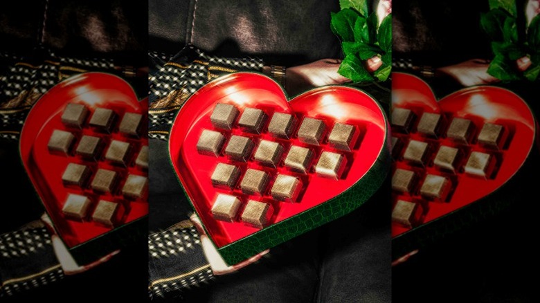 chocolates covered in gold dust in a heart-shaped box with a red interior and green exterior