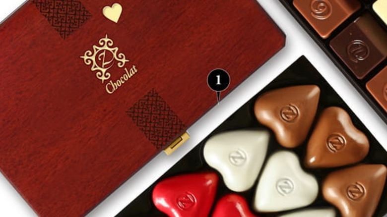 A wooden box has heart- and rectangle-shaped chocolates.