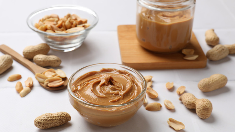 Ramekin of peanut butter by peanuts and spoon