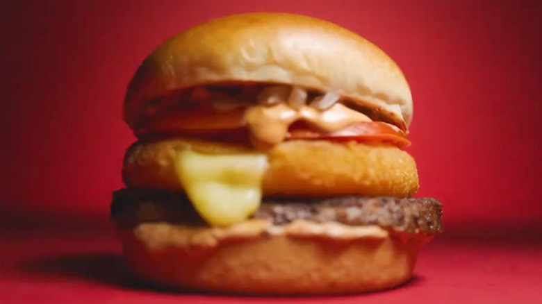 Burger with cheese patty, a tomato slice, and sauce