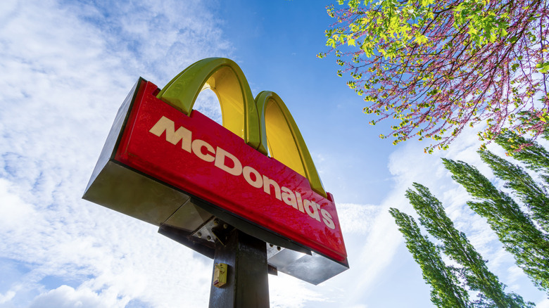 Ground view of a McDonald's golden arch sign next to trees