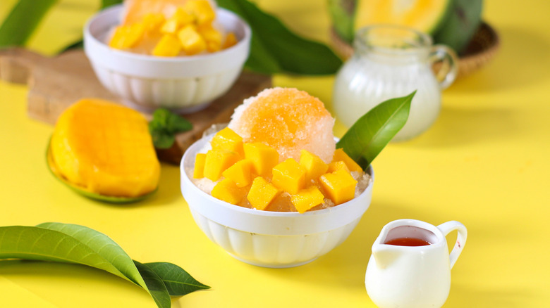 mango bingsu on yellow background garnished with leaves