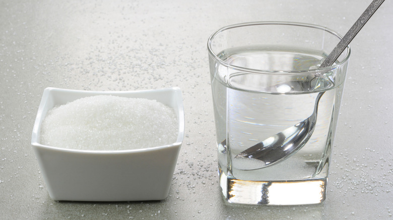 A pile of sugar next to a glass of simple syrup