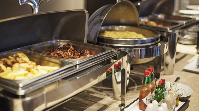 a row of chafing dishes full of food at a buffet