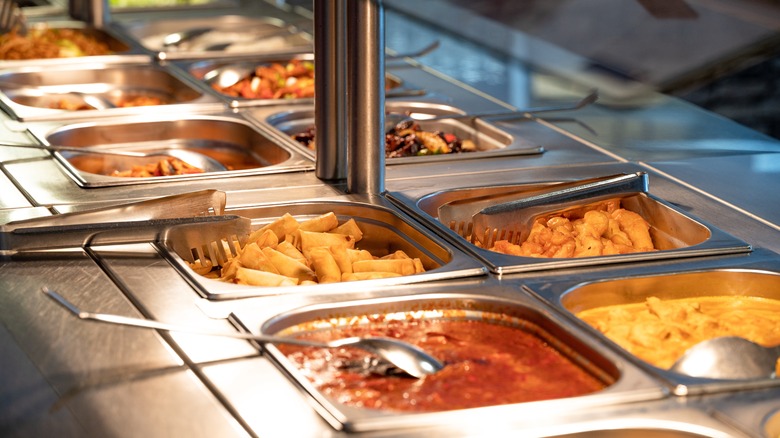 Various dishes at a buffet with serving utensils