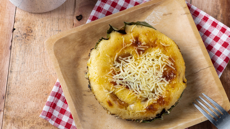 bibingka on a wooden plate on top of a red-checked napkin