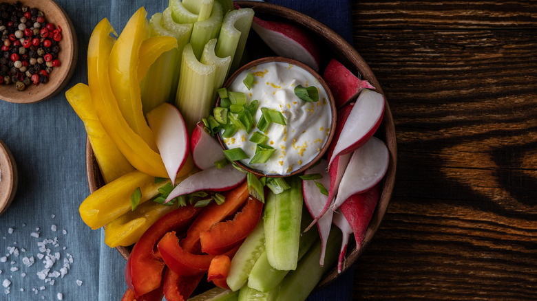 crudites with a yogurt dip on a wooden table with a blue cloth napkin