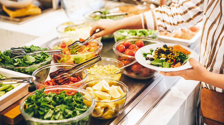 Woman choosing food from a buffet in the salad station