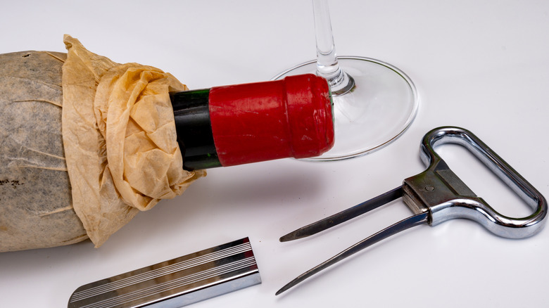 A cork puller laying next to an old wine bottle