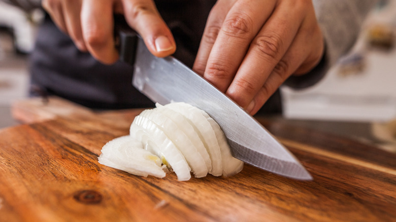 Cook chops onions with knife on cutting board