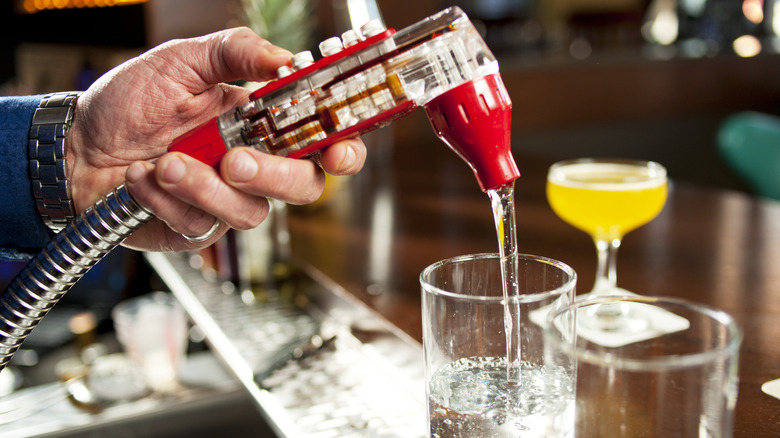 bartender using soda gun to add soda to a mixed drink