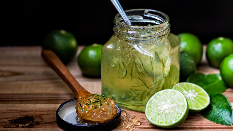 Jar of lime marmalade with limes and wooden spoon