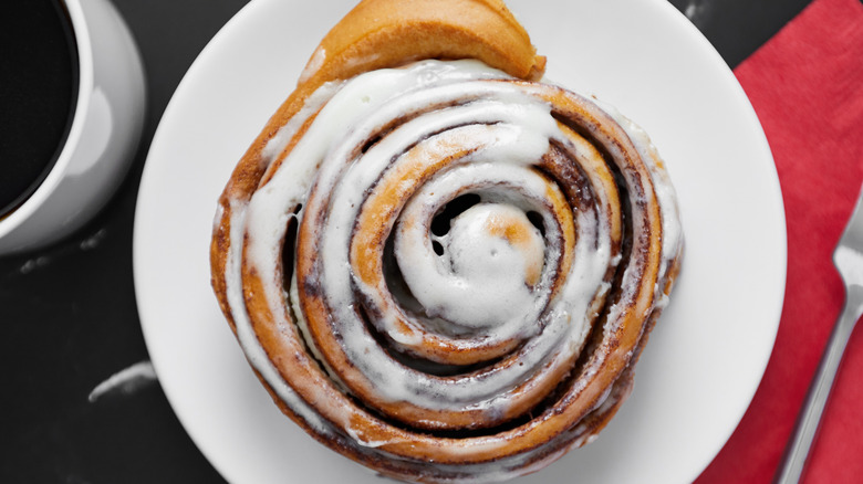 A large glazed cinnamon roll on a white plate