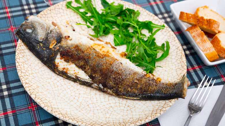 grilled whole branzino on a plate with arugula