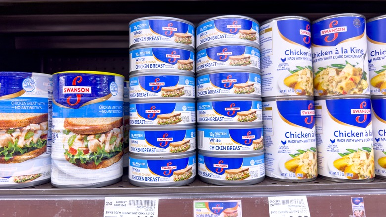 Stacked cans of Swanson chicken on grocery store shelf