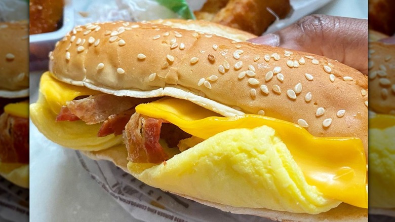 Person holding breakfast sandwich