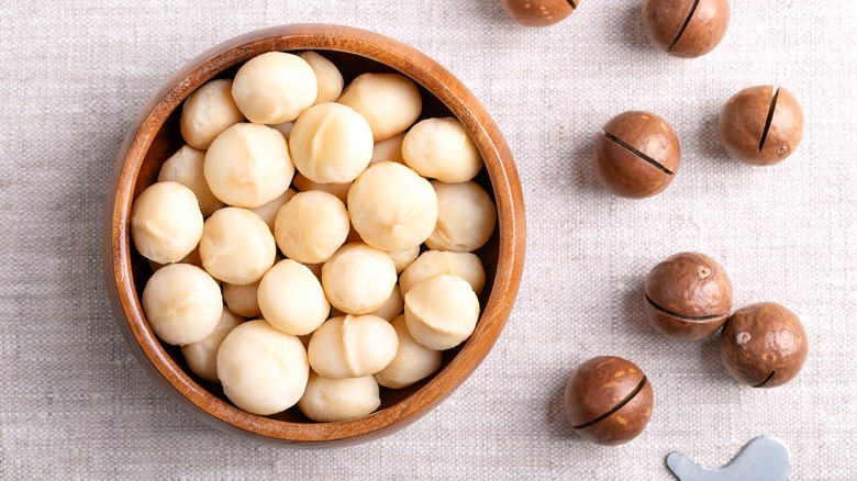 Bowl of macadamia nuts beside shells