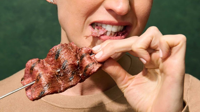 Person eats cultivated steak on skewer