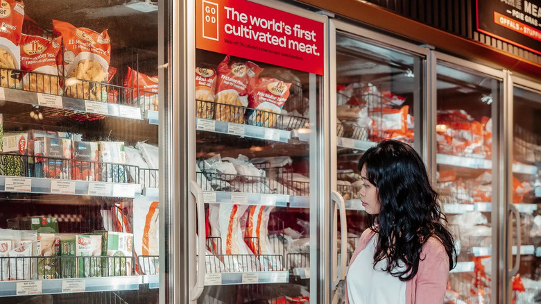 Person looking at cultivated meat products in fridge