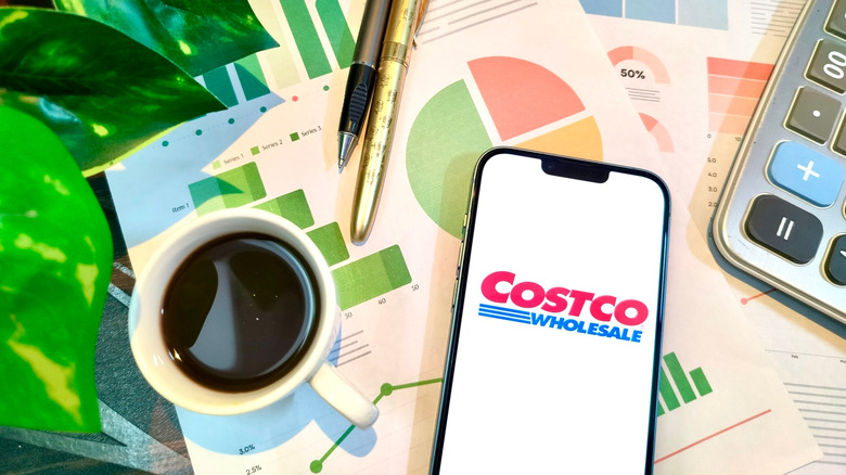 Spreadsheets, coffee, pens, and phone with Costco logo